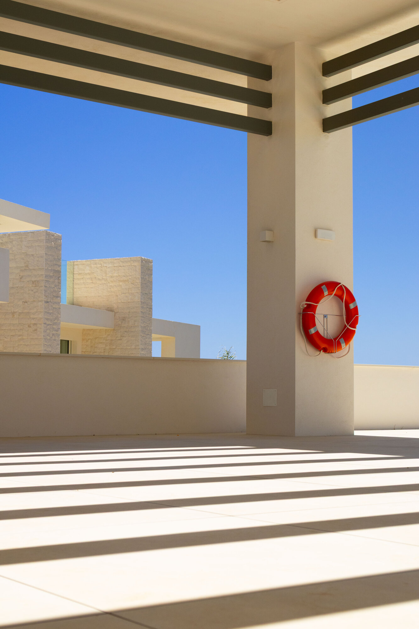 Pergola shadows and a lifebuoy on a column